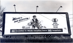 A billboard with a man holding an unconscious woman with the text, "Where's the Hospital!, 33 Counties in North Carolina have no hospitals, back the good health plan!"