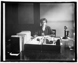 A black and white photo of Julia Lathrop sitting at a desk.