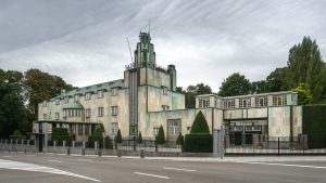 A three-quarter view of the Palais Stoclet, a creamy stone exterior with green highlights in the Art Deco style.