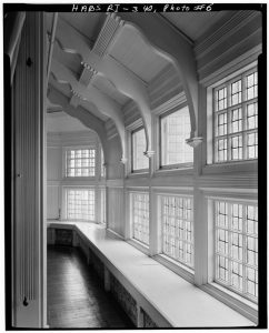 Large casement windows bring abundant light into the second floor.  Brackets support the ceiling and a bench provides ample seating all along the window wall.