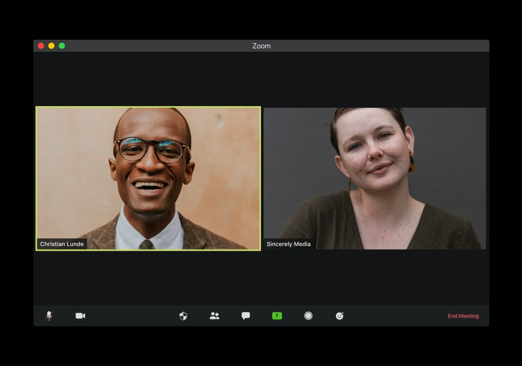 A computer screenshot that shows two people using Zoom to video chat, both looking forward at their cameras and smiling