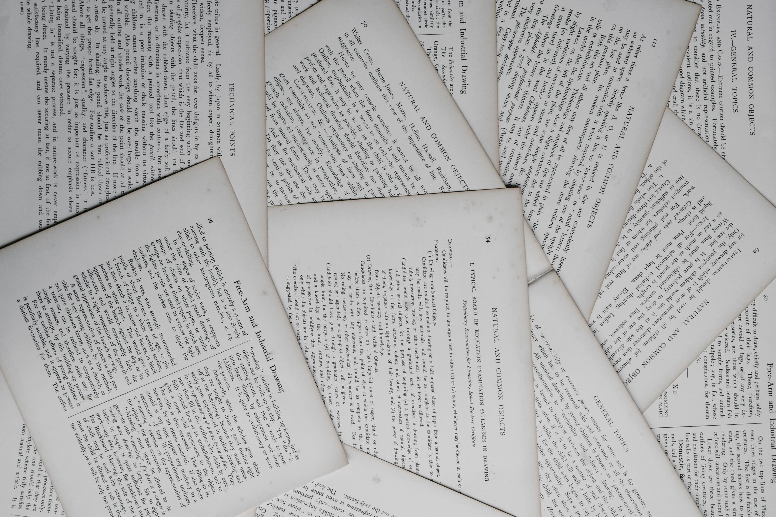 Photograph of printed pages spread across a surface, overlapping and filling the image.